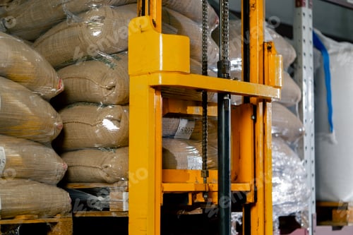 Preview: close up A worker at coffee factory uses a yellow lifting fork to lift and insert forks into pallets