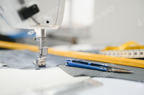 Preview: Composition of sewing thread, scissors and tape measure on a white table.