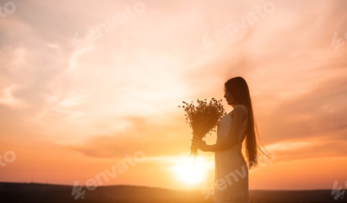 Preview: Woman Holding Flowers in Field at Sunset