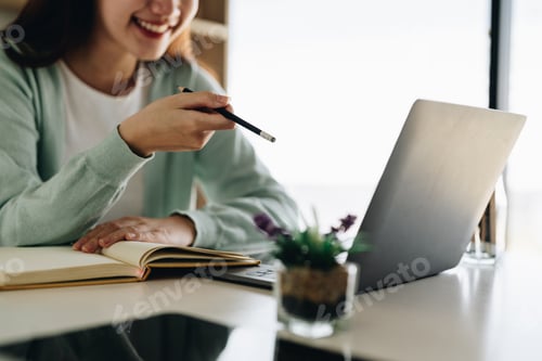 Preview: Concentrate asian gial freelancer wearing headset, communicating with client via video computer