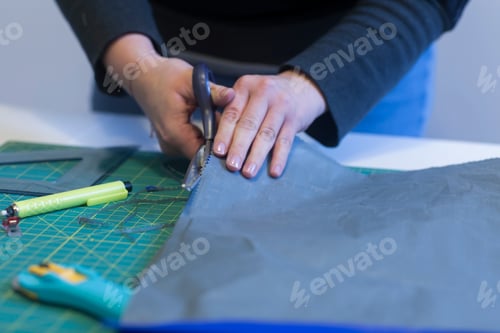 Preview: Hands meticulously cutting fabric on a cutting mat for a craft project.