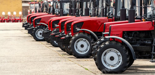 Preview: Agricultural red coloured tractors in a row. Agricultural equipment dealership background.