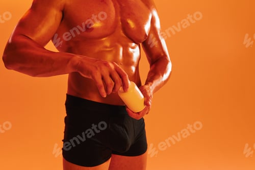 Preview: Man bodybuilder boxer with naked torso with abs holding can muscle growth pills, steroids, doping
