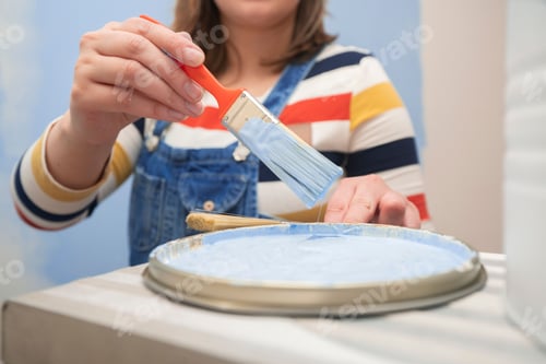 Preview: woman's hand taking out a brush with blue paint from a tray