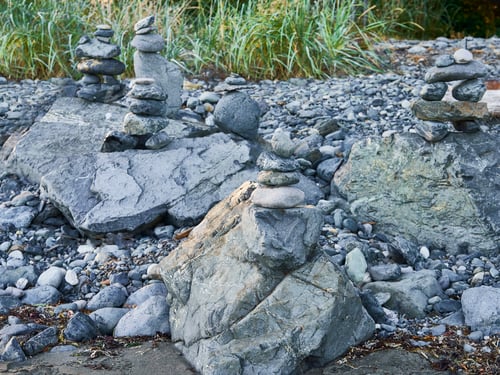 Preview: Inukshuks created out of gray rocks on top of boulders at Jordan River Beach