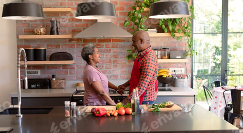 Preview: Happy african american senior couple cooking together in kitchen