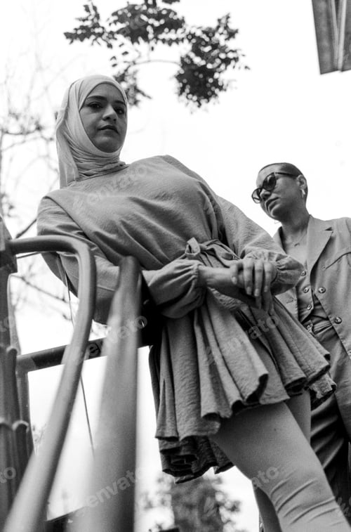 Preview: Urban portrait of female friends posing leaning on a banister.