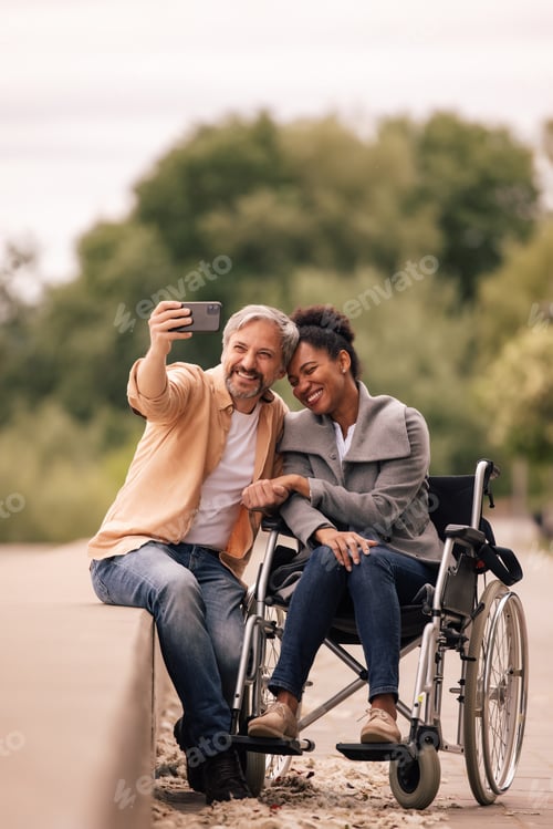 Preview: Adult man taking photo of him and his disabled woman.