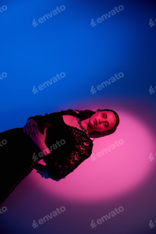 Preview: Stylish young woman poses in a vibrant pink and blue studio setting