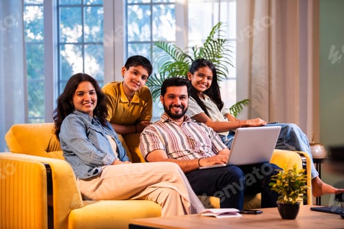 Preview: Indian parents and kids enjoying online browsing and shopping together on laptop at home