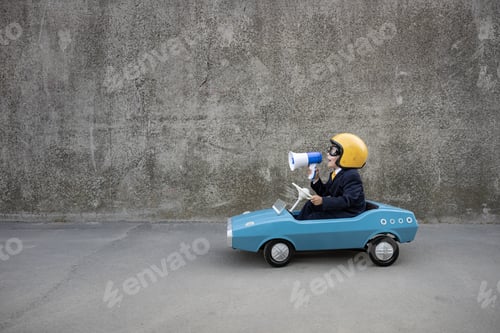 Preview: Funny businessman driving retro pedal car outdoor