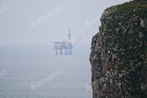 Preview: View of the cliff against the oil rig in the distance.