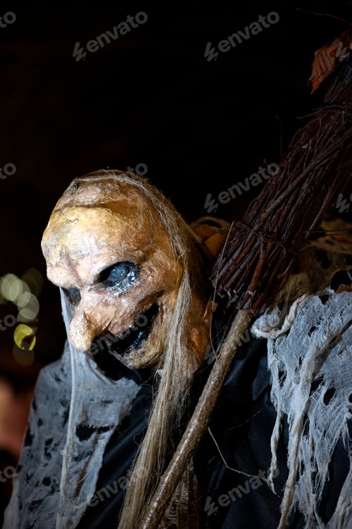 Preview: Witch with a broom and a monster face on a dark halloween horror night