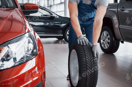 Preview: A mechanic with a tire bus in a repair garage. replacement of winter and summer tires