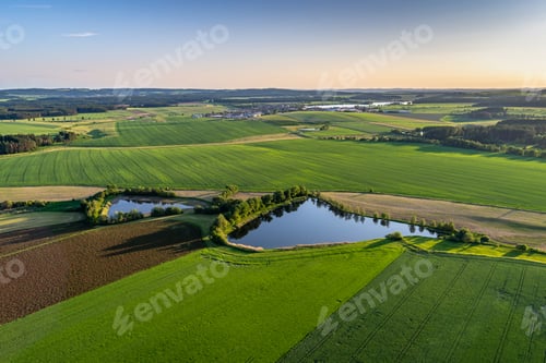 Preview: Bird's-eye shot of breathtaking green fields with small ponds in a rural area