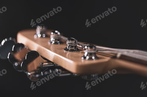 Preview: Close-up of a bass guitar fretboard on a blurred dark background.