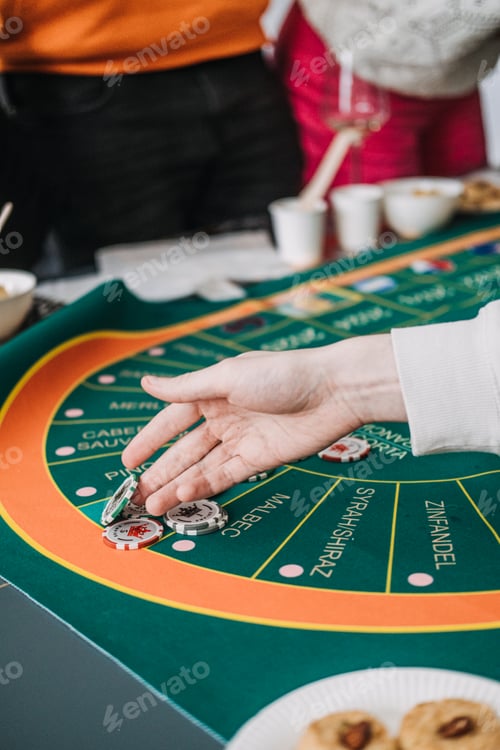 Preview: Hands playing at a wine-themed casino game, with glasses of rose in the background, blending