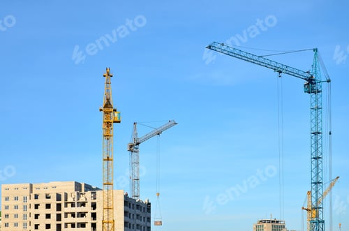Preview: Working tall cranes inside place for with tall buildings under construction against a clear blue sky