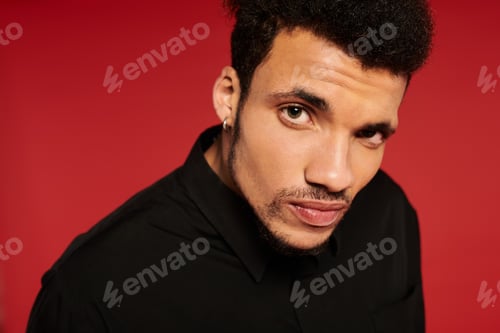 Preview: Handsome young man posing with a confident expression against a striking red background