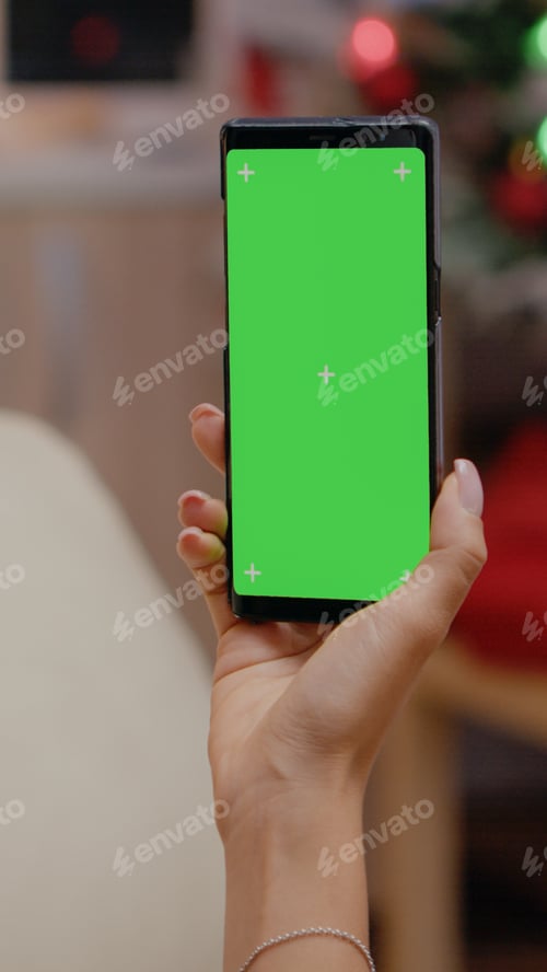 Preview: Close up of adult vertically holding smartphone with green screen