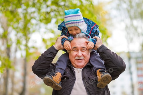 Visualização: Foto de um homem sênior feliz sorrindo, desviando o olhar, seu neto o abraçando