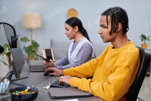 Preview: Two young people writing code in office black man in foreground