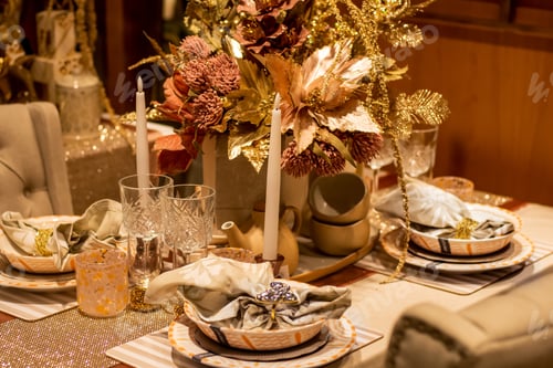 Preview: Elegant Christmas dinner table set decoration in gold with glasses, candles and plates