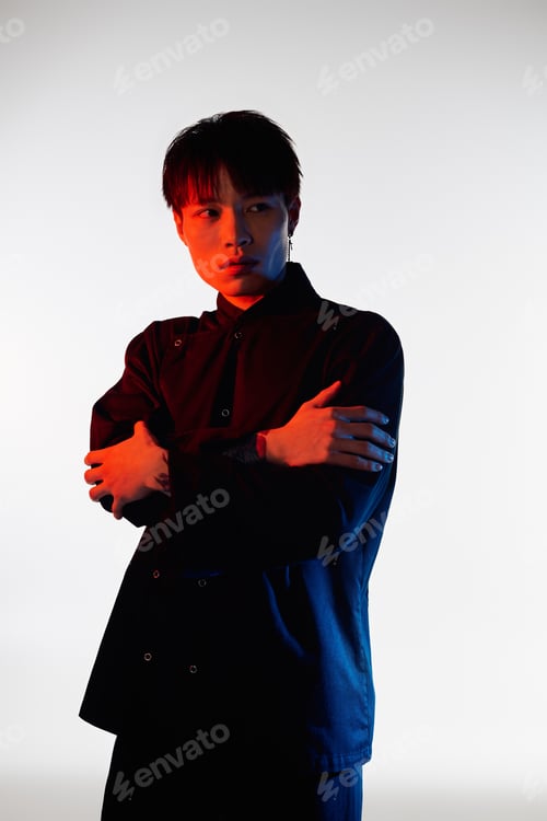 Preview: Stylish young man showcases modern fashion in striking studio lighting at dusk