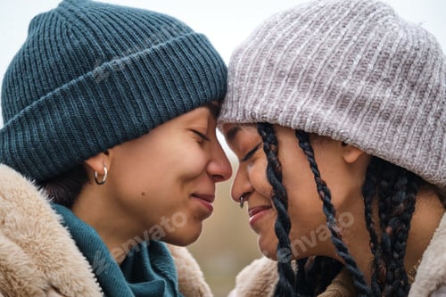 Preview: Dominican lesbian couple smiling showing affection and love at street in winter.