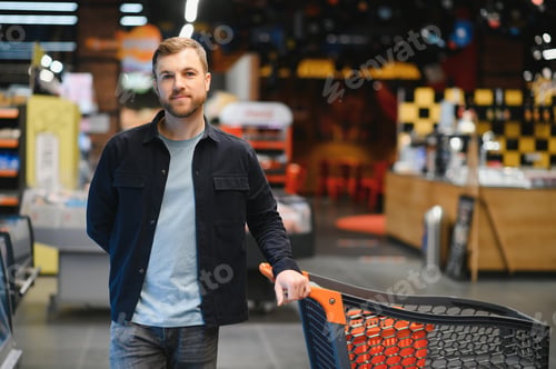 Preview: Young man buying groceries at the supermarket. Other customers in background. Consumerism concept.