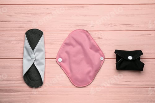 Preview: Many reusable cloth menstrual pads on pink wooden table, flat lay