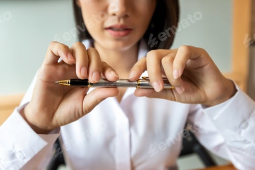 Preview: Beautiful young Asian woman holding a pen in her hand. Business concept.