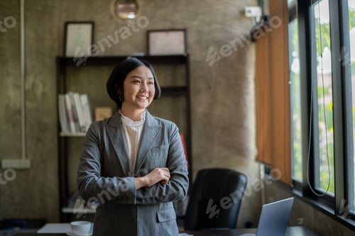 Preview: A woman in a business suit stands in front of a desk with a laptop on it