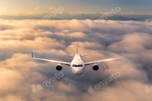 Preview: Airplane is flying above the clouds at sunrise in summer