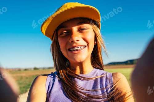 Preview: Beautiful teen girl taking selfies in a yellow cap and bracket on her teeth.