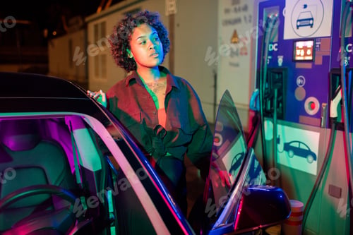 Preview: Young woman getting out of electric car to have it charged
