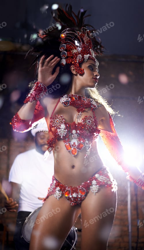 Preview: Ravishing in red. Shot of a beautiful samba dancer performing in a carnival with her band.