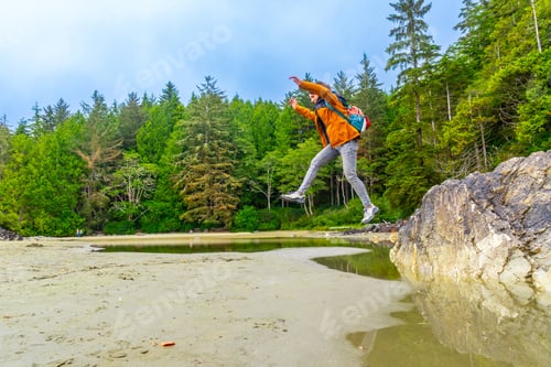 Preview: Backpacker jumping over tide pool in tofino, vancouver island