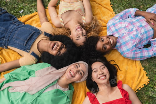 Preview: Happy youth, multiethnic women having fun lying on the grass in the park