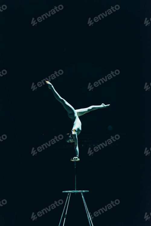 Vista previa: KYIV, UKRAINE - NOVEMBER 1, 2019: Gymnast performing handstand in circus isolated on black