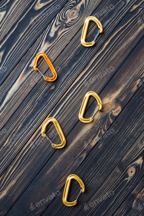 Preview: Isolated photo of climbing equipment. Parts of carabiners lying on the wooden table
