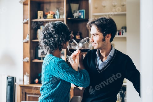 Preview: Young handsome mixed race couple in their house having a glass of red wine