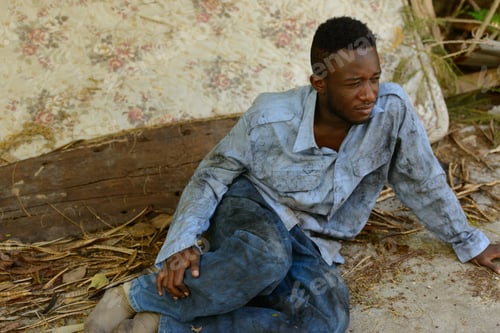 Preview: Sad young homeless African man sitting in the streets