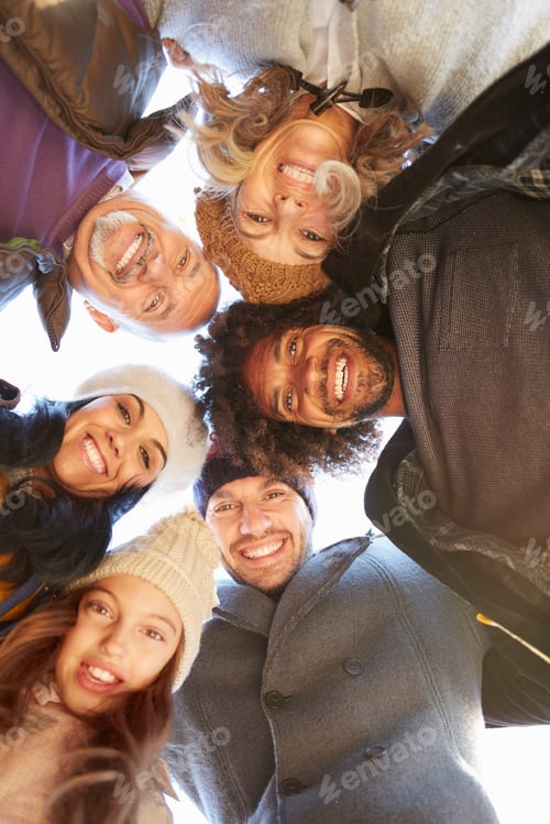 Preview: Multi generational family in a huddle bending forward looking down at camera smiling