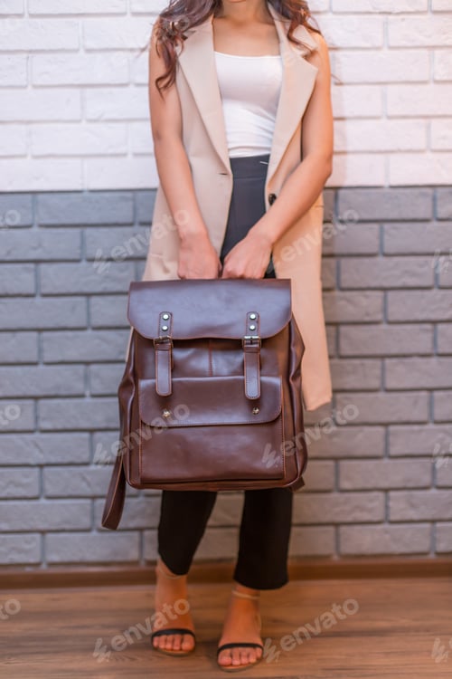 Visualização: Mulher segurando mochila de couro marrom na mão