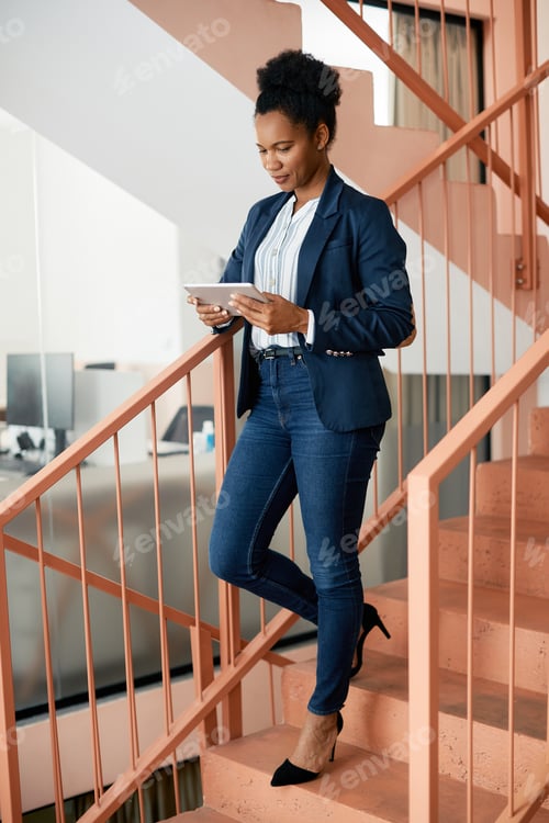 Preview: Black businesswoman using digital tablet on a staircase.