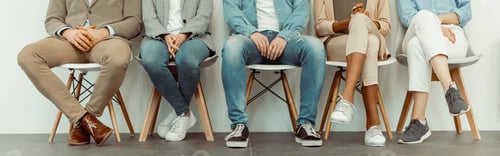 Preview: Colleagues sitting on chairs along the wall
