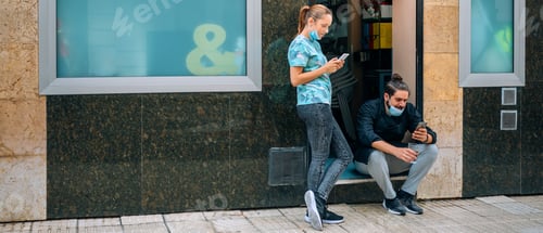 Preview: People Social Distancing Using Phones Outside Building