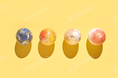 Preview: Colorful marbled balls on yellow background with shadows casting patterns