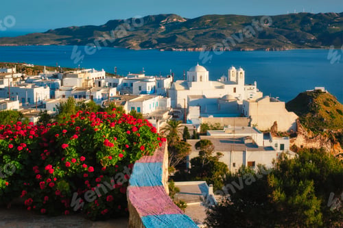 Preview: Picturesque scenic view of Greek town Plaka on Milos island over red geranium flowers